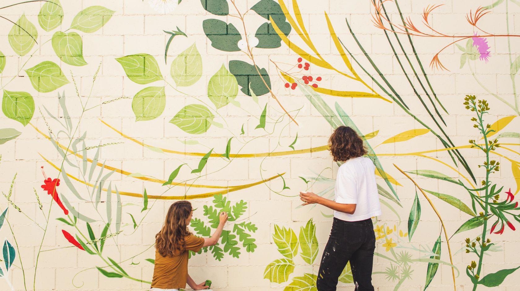 two women working on a mural painting at the piccolo
